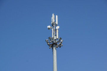 Fototapeta na wymiar Mobile phone communication antenna tower with satellite dish on blue sky background, Telecommunication tower