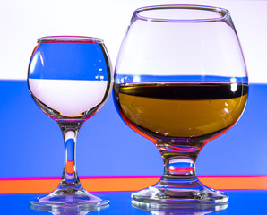 A glass of vodka and a glass of brandy, whiskey or bourbon on a white or colored background