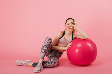 Happy sportswoman sitting on the floor with fitness ball