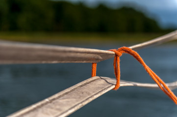 cienki pomarańczowy sznurek zawiązany na pasach (krawat)