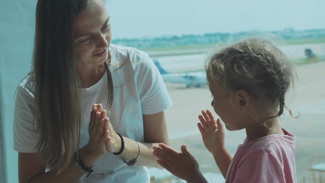 Yound mother and little cute daughter having fun at airport in slow motion.