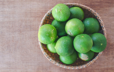 Fresh lemon or lime from the garden in a brown basket on a wooden table Agricultural products concept.