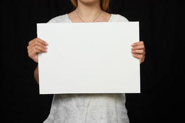 Female hands holding blank sheet of paper isolated on black