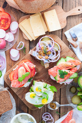 Variants of traditional Danish open sandwiches on rye bread for breakfast on a wooden table, top view, selective focus