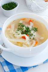 Hot homemade soup on chicken broth with homemade noodles in a white cup, selective focus
