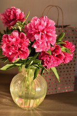 Fresh bouquet of pink peonies peony roses flowers in a vase on table in room. A gift to a mum's day. Sunny day background. Blossom wallpaper. Card, copy space.