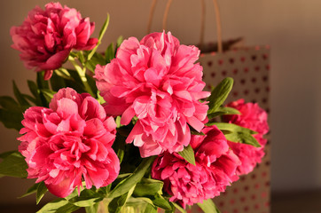 Fresh bouquet of pink peonies peony roses flowers in a vase on table in room. A gift to a mum's day. Sunny day background. Blossom wallpaper. Card, copy space.