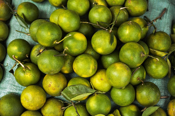 Pile of green unripe oranges background. Many tropical citrus fruit for sale at a food market