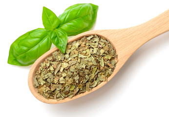 dried basil leaves in the wooden spoon, isolated on white, top view