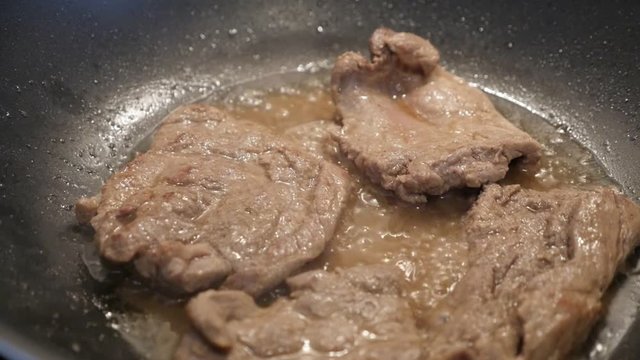 Pork steaks frying in wok slow-mo footage - Slow motion meat preparing in hot oil close-up
