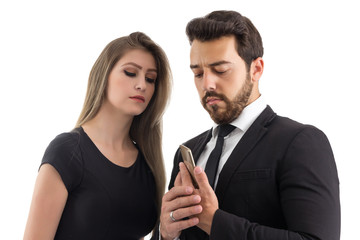 Man hides the screen of the curious woman's cell phone. The two are dressed in black. Fashionable clothes..