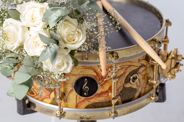 The white rose drumsticks is placed on a snare drum. There are nobody.