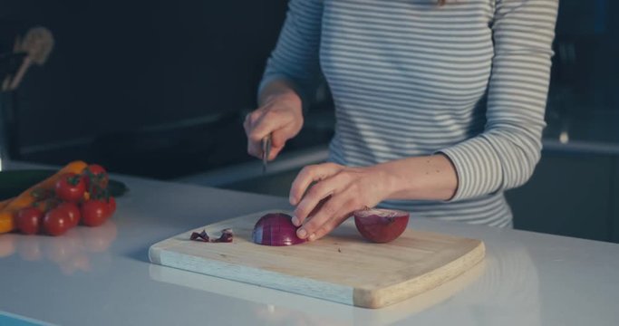 Young woman chopping onions in her kitchen