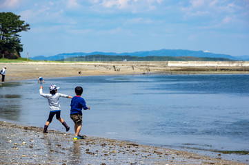 海辺で石を投げて遊ぶ子供たち