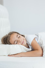 Smiling little girl sleeping on the bed. Space for text
