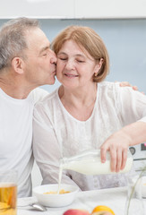 elderly man kisses his wife in the kitchen