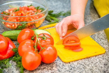 female hands cut a tomato