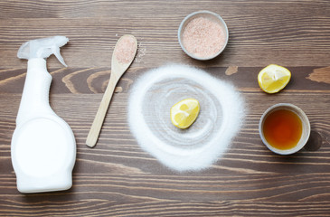 Eco friendly natural cleaners baking soda, salt, lemon and vinegar on a wooden background.