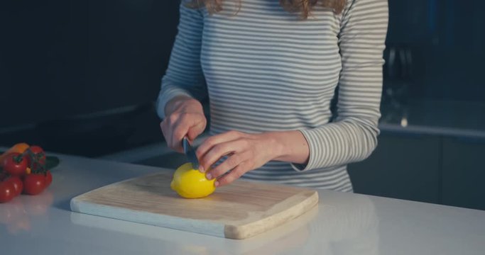 Young woman cutting a lemon in her kitchen