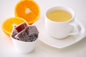 orange marmalade candy with a cup of tea on white table