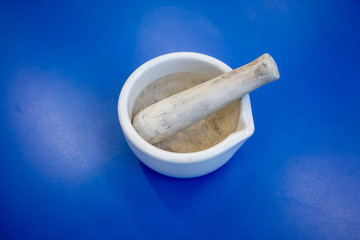 Mini white mortar and pestle porcelain for medicine grinder isolated on blue