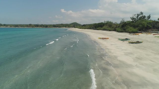 Beautiful tropical beach Cabugao with white sand and palm trees in the Philippines, Luzon. Aerial view of coast with beach and turquoise water.