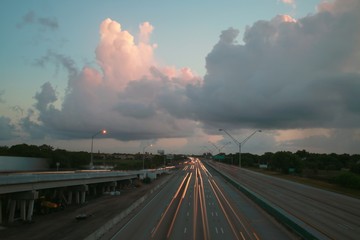 Traffic moves steadily along I-95 north and south on a hot sunny morning just before dawn in rush hour under a cloudy sky in a long time exposure