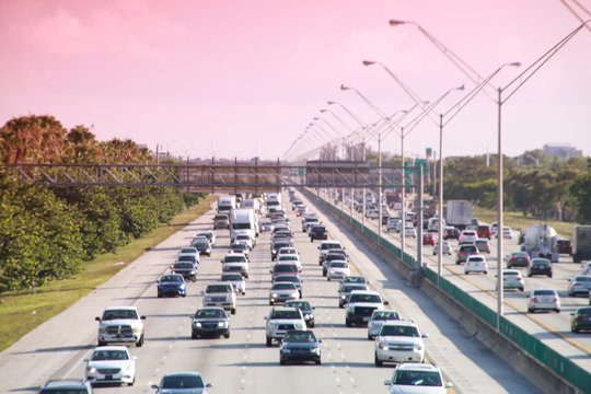 Traffic moves steadily along I-95 north and south in a hot sunny morning in rush hour accented by a red graduated filter.