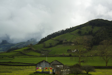Obraz premium Stunning Green rolling hills landscape with fog and a house in ruins