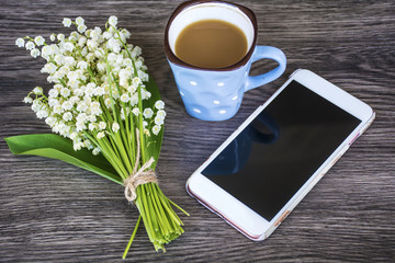 Obraz na płótnie Canvas Bouquet of Lily of the Valley ,Mobile Phone and Cup of Coffee for Good Morning .Spring Morning Concept