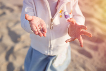 young child, little kid on the sandy beach. sand on palms close up
