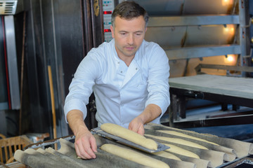 Baker preparing baguettes for baking