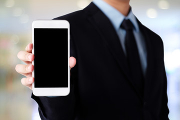 Businessman hand holding smartphone with blank on screen display over blur background, business people and technology display montage, mock up, template, background