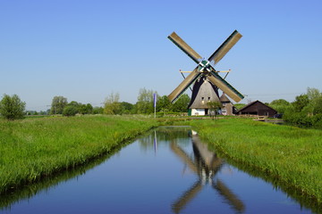 Typical Dutch traditional wooden windmill reflecting in the water.