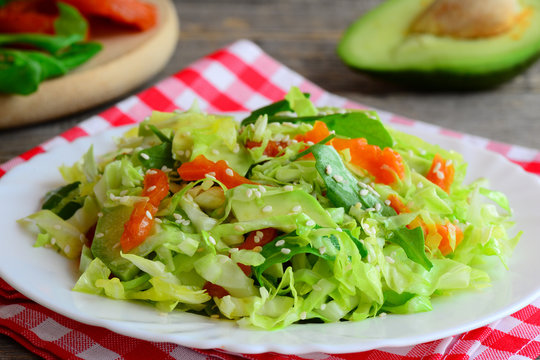 Simple vegetarian avocado coleslaw. Home coleslaw salad with fresh avocado slices, dried apricots, green arugula and sesame seeds on a plate. Healthy food diet. Clean eating recipe for weight loss