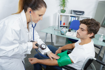 doctor measures the blood pressure of a patient young man