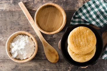 Arepas in iron pan on wooden table. Venezuelan typical food. Top view