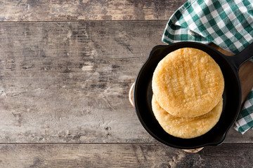 Arepas in iron pan on wooden table. Venezuelan typical food. Top view. Copyspace