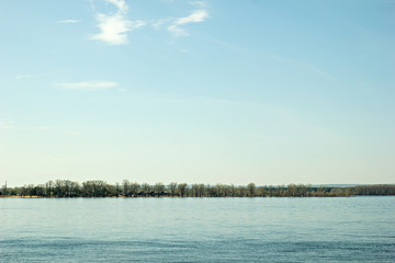 View of the right bank of the Volga River - trees and summer houses opposite the embankment of Samara city during the spring flood
