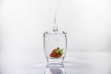 Bicchiere di acqua fresca con fragola tuffata dentro
