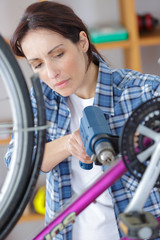 young woman is fixing her bike