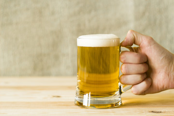 A mug of beer in the man's hand.