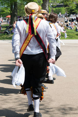 Morris Men wearing bells and white shirts and stockings dancing on May Day Bank Holiday with sticks...