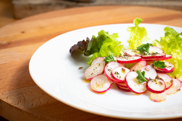 Healthy food organic slices radish salad in white plate on wood board