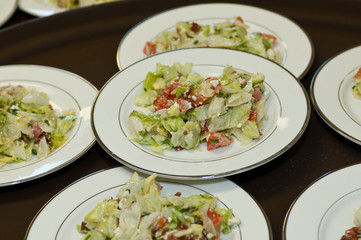 Fresh green salad with feta cheese and tomatoes on party plates