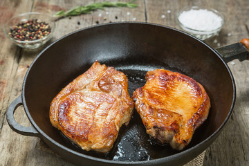 Fried pork chops in a pan with pepper and salt. 