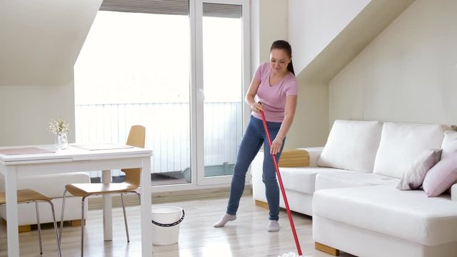 people, housework and housekeeping concept - happy woman or housewife with mop cleaning floor and dancing at home