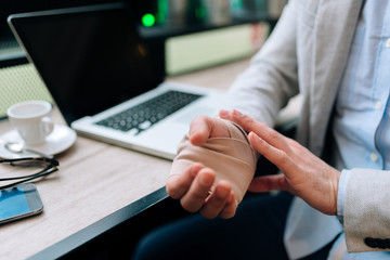 Men with injured bandaged hand sitting at the table in the cafe. Close-up