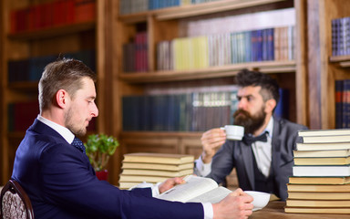 Men with busy faces reading books, studying and drink tea.