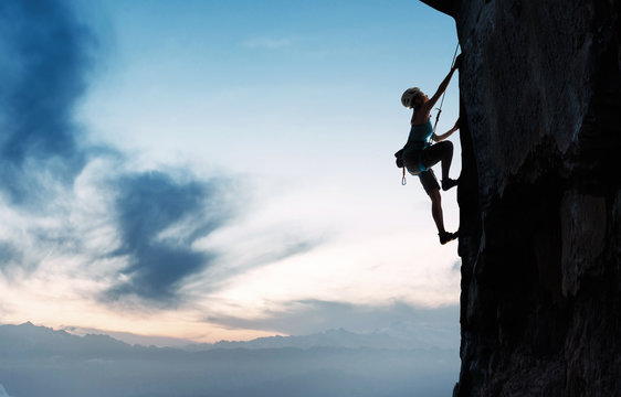 Young woman on the cliff rock climbing